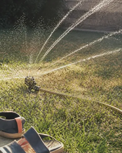 午後逆光中灑水器、水珠、濕草地與舊帆布涼鞋底片快照