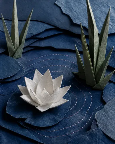 手工紙材拼貼／立體組構作品，深淺靛藍摺紙層疊成池水，白色摺蓮與縫線漣漪位在中央。直幅構圖保留清楚主體與手作質地。