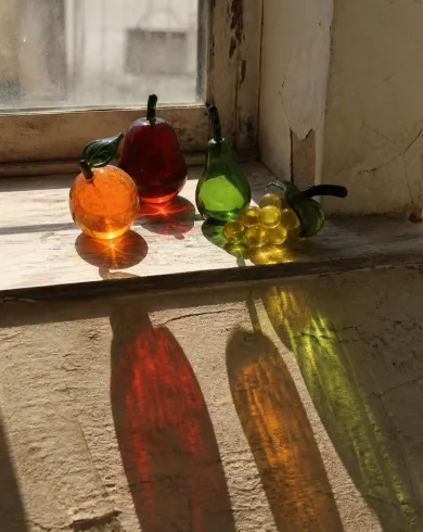 靜物與生活攝影／自然光作品，描繪彩色玻璃果實在舊窗台投下紅、綠與琥珀色影子。直式構圖保留清晰主體、自然材質與光線細節。
